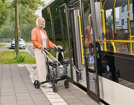 Frau steigt mit einem Rollator in den Bus